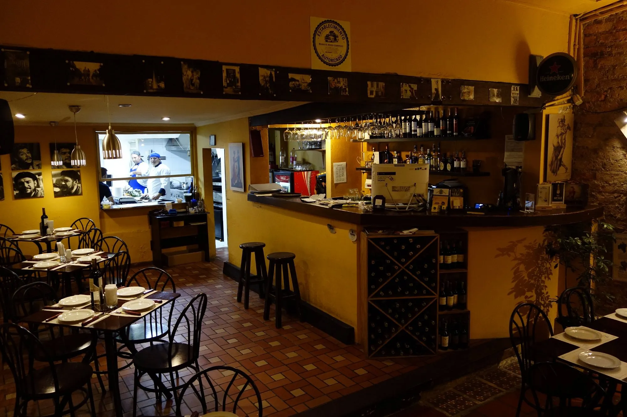 Chef preparing grilled meat in a warmly lit restaurant with rustic decor, inviting atmosphere, and guests enjoying their meals